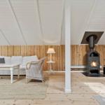 Wohnzimmer mit Sofa, Sessel und Kaminofen an Holzwand