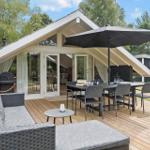 Terrasse mit Sitzgruppe, Tisch, Sonnenschirm und Grill. Durchgehende Glasfront zum Innenraum.