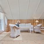 Wohnzimmer mit Sitzgruppe, Kamin und Holzwand. Durchgang zur Terrasse mit Grill.