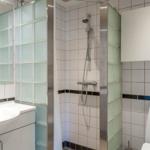 Badezimmer mit Dusche, Waschbecken und Toilette. Fliesenwand und Glaswand.