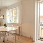 Esszimmer mit runden Tisch, weißen Stühlen und Balkontür.