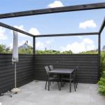 Terrasse mit Tisch, Stühlen und Sonnenschutz unter einem Pavillon.