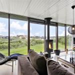 Wohnzimmer mit Kamin, großem Fenster und moderner Einrichtung.