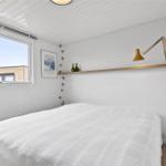 Schlafzimmer mit weißem Bett, Fenster und Wandlampe.