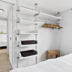 Schlafzimmer mit Kleiderschrank, Fenster und Betten im Hintergrund.