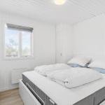 Schlafzimmer mit weißem Bett, Fenster und Holzboden.