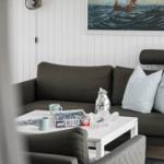 Ein Wohnzimmer mit grauem Sofa, weißem Tisch und Wandbild mit Segelboot.