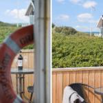 Terrasse mit Tisch, Stühlen und Rettungsring. Blick auf das Haus und den Strand.