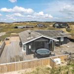 Haus mit Holzterrasse, Whirlpool und Blick auf Dünenlandschaft.