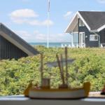 Von Fenster aus Blick auf Strandhaus mit grüner Vegetation und Meer.
