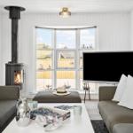 Wohnzimmer mit Kamin, Sofa, Fernseher und Blick auf den Hafen.