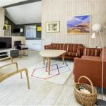 Wohnzimmer mit Sofa, Tisch und Fernseher. Holzwand und helles Parkett.