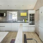 Moderne Küche mit weißen Schränken, Kühlschrank und Fenster.