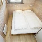 Schlafzimmer mit Bett, Holzwand und Fenster