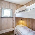 Zimmer mit Doppelstockbett, Holzwand und kleinem Fenster.