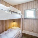 Zimmer mit Doppelstockbett, Holzwand und Fenster.