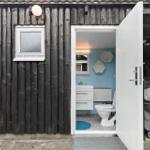 Badezimmer mit Toilette und Waschbecken, blaue Wände, weißes Mobiliar.