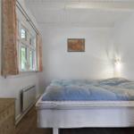 Schlafzimmer mit Bett, Fenster, Gardinen und Wandbild.