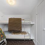 Zimmer mit Doppelbett und Schlafcouch, brauner Fliesenboden und weißer Tür mit Schloss.