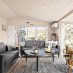 Living room with two sofas, round table, and large windows. Wooden walls and ceiling.