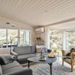 Living room with sofa, armchair, and table. Large windows offer view of outdoor area.