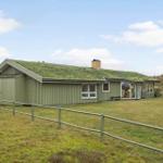 A house with a grass roof and large windows in a rural setting.