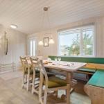 Dining area with wooden table, green cushions, and view of greenery through window.