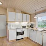 Kitchen with white cabinets, stove, and dishwasher. Window with view of greenery.