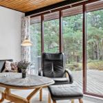 Wohnzimmer mit schwarzen Ledermöbeln, runden Tisch und Blick auf Wald.