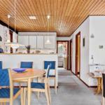 Ein Essbereich mit blauen Stühlen und einem runden Tisch. Küche und Wohnzimmer sind sichtbar.