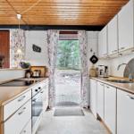 Küche mit weißen Schränken und Holzoberflächen, Blick auf Außenbereich.