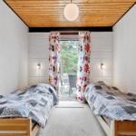 Zwei Betten mit gemusterten Bettdecken, Holzdecke und Blick auf Balkon mit Sitzgelegenheiten.