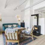 Wohnzimmer mit Kamin, Sofa und Holzboden. Blick in die Küche.