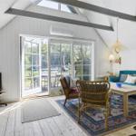 Wohnraum mit Sofa, Stühlen und Blick auf Garten. Holzboden und weiße Wände.