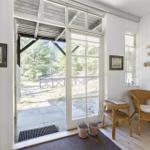 Eingangsbereich mit Rattan-Sessel, Pflanzen und Blick auf den Garten.