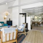 Wohnbereich mit Sofa, Sitzgelegenheiten und Kamin. Holzboden und weiße Wände.