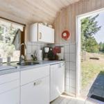 Küche mit Spüle, Kaffeemaschine und Waschmaschine. Durchgang zu einem Garten mit Bäumen.