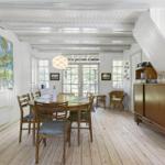 Esszimmer mit Holzboden, Tisch, Stühle und Kamin. Wandkarte und Holzschrank sichtbar.