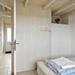 Schlafzimmer mit Bett, Kleiderhaken und Schrank. Durchgang zur Küche und Flur.