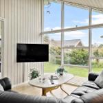 Wohnzimmer mit Sofa, TV und großem Fensterblick auf Garten.