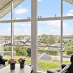 Zwei schwarze Sessel und ein Tisch vor großen Fenstern mit Blick auf Grünflächen und Häuser.