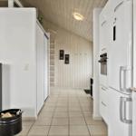 Küche mit weißen Geräten und Holzwand im Hintergrund.