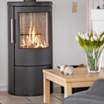 Kaminofen mit brennendem Feuer im Wohnbereich mit Tisch und Stühlen.