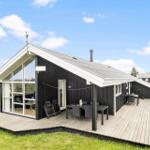 Moderne Holzhütte mit großem Balkon und Terrasse mit Sitzgelegenheiten.