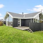 Moderne Villa mit Holzverkleidung und großem Fensterbereich auf grünem Grundstück.