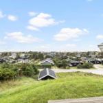 Weitläufiger Blick auf Wohngebiet mit Häusern und Grünflächen unter blauem Himmel.