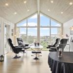 Großes Wohnzimmer mit Blick auf die Landschaft und schwarzen Sesseln.