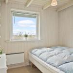 Schlafzimmer mit Bett, Fenster und weißen Wänden.