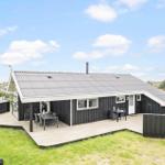 Ein Haus mit Holzterrasse und Garten. Außentisch und -stühle sind vorhanden.