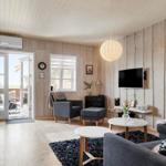 Living room with wooden walls, seating furniture, and TV mounted on the wall.